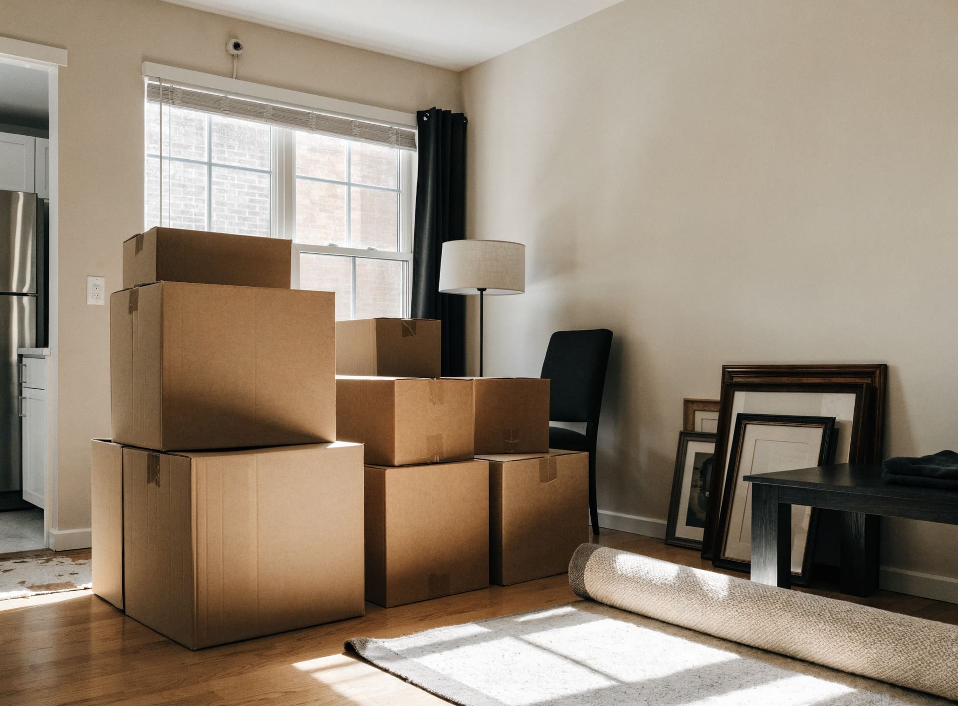 Representative photograph: packed boxes, a rolled rug and framed pictures in a living room