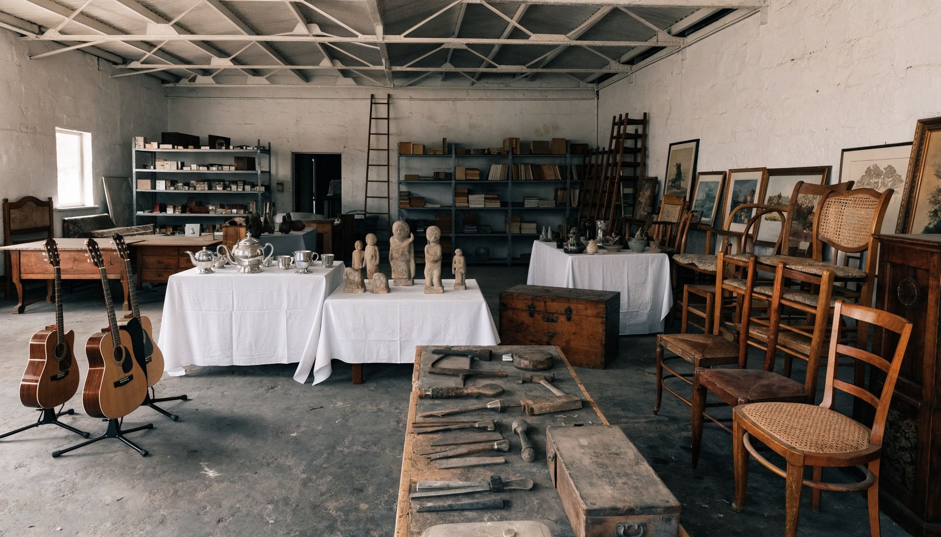 Representative photograph: guitars, silver, sculptures, tools and chairs grouped for an auction preview